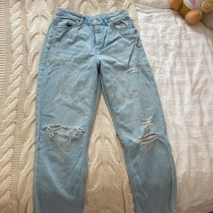 Ljusblå ripped jeans med fransar - Säljer ett par ljusblå jeans med snygga slitningar och fransade benslut. Jeansen har klassisk femficksdesign och relaxed fit. Materialet är mjukt denim och färgen är riktigt fräsch ljusblå.