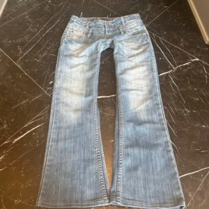 Ljusblå bootcut jeans med broderade fickor - Snygga ljusblå jeans med bootcut passform och coola broderade detaljer på bakfickorna. Klassisk femficksmodell med slitningar och ljus tvätt. Inga defekter 💕passar S