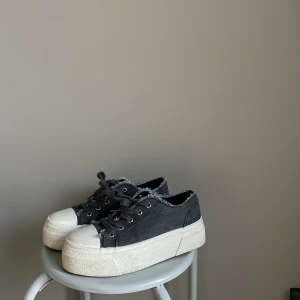 Grå sneakers med platåsula - Svarta sneakers med vit platåsula och fransiga kanter. Skorna har snörning och en rund tå. Skorna är från even&ODD i st 37 🩶 