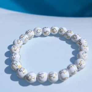 Vitt pärlarmband med gulddetaljer - Stilrent armband med vita runda pärlor, dekorerade med guldfärgade kors på varje pärla. Perfekt accessoar för dig som gillar unika detaljer och enkel design. Elastiskt band gör det lätt att ta på och av. Passar yngre barn nytt