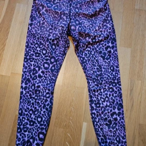 Rosa leopardmönstrade leggings  - Snygga rosa leggings från Fabletics med leopardmönster. De är högmidjade och gjorda i mjukt, fukttransporterande polyestertyg med power mesh-detaljer. Perfekta för träning eller när du vill sticka ut lite extra. Förstärkta med shorts i,  ficka på insidan till tex mobilen. 