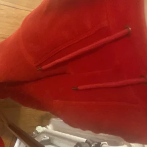 Röda fleece täckbyxor med snörning - Säljer ett par röda täckbyxor i mjuk fleece med snörning i midjan och dragkedja framtill. Byxorna har praktiska fickor och en loose passform, perfekta för kalla dagar eller vinteraktiviteter.