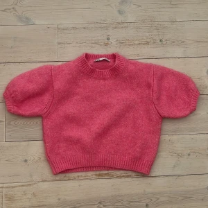 Rosa stickad tröja från Zara - Superfin rosa stickad tröja från Zara med korta puffärmar och ribbade muddar vid hals, ärmslut och nederkant. Tröjan har en croppad passform.