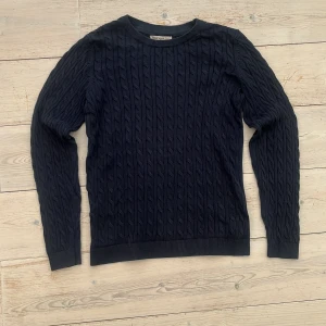 Mörkblå kabelstickad tröja Basic You - Kabelstickad tröja i mörkblått från Basic You. Gjord i ekologisk bomull, med rund halsringning och långa ärmar. 