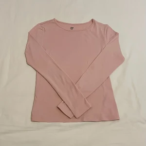 Ljusrosa tight långärmad tröja  - Enkel och stilen ljusrosa tight långärmad tröja från H&M. Tröjan har rund halsringning och är tillverkad i mjuk bomullsmix som känns skön mot huden. Perfekt att matcha med jeans eller kjol för en clean look.