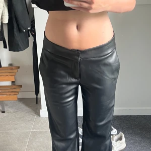 Svarta skinnbyxor med låg midja - Snygga svarta skinnbyxor med låg midja och raka ben. Byxorna har minimalistisk design med diskreta fickor bak och slät framsida utan synliga detaljer. Perfekta för en edgy och trendig look. Säljer då dem är för stora för mig, skriv för frågor🙌🏻💞