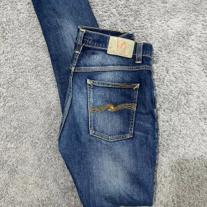 Nudie Jeans Blå - Väldigt fin mörk blå washed färg av nudie jeans i storlek 29/28. Använt några gånger men i väldigt bra skick. Skick 9/10. Hör av dig om du har frågor :)