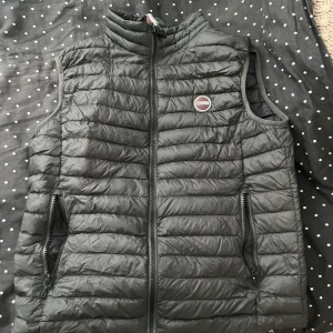 Grön dunväst från Colmar - Snygg grön dunväst från Colmar med quiltad design och hög krage. Västen har dragkedja framtill och två praktiska fickor med dragkedja. Perfekt att slänga över en hoodie eller tröja för extra värme. Priset går att diskuteras 