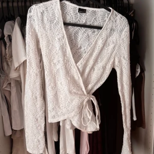 Vit spetsomlottopp med knyt - Superfin vit omlottopp i spets med långa ärmar och knyt i sidan. Trådet som man knyter med är lite sönder men de syns inte och går ändå att knyta🥰