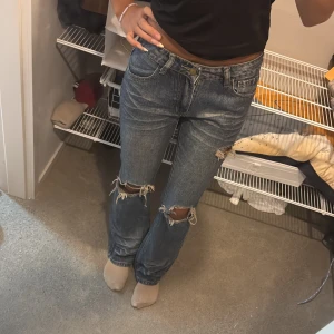 Blå bootcut jeans med hål - snygga blåa jeans med hål i storlek S. köpta utomlands så har inget specifikt märke. Hålen är självklippta! jeansen är lite imellan low waist och mid waist men de passar jättebra och är i bra condition 