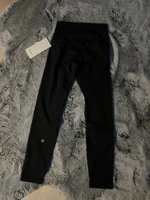 Svarta Align Tights från Lululemon 25” - svarta align leggings från Lululemon med hög midja och tight passform. Outerseem:84cm. innerseem:64cm(25). Tillverkade i ett stretchigt och mjukt material som sitter skönt mot kroppen. Perfekta för träning eller chill. Diskret logga vid benet och stilren design.