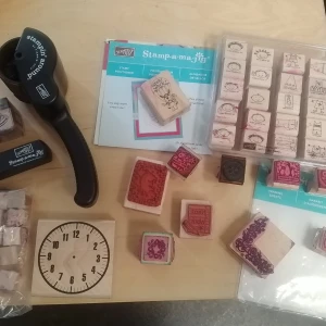 Stort kit med stämplar och verktyg - Säljer ett komplett kit med olika stämplar i trä och gummi, inklusive motiv som klocka, blommor och ramar. Flera stämpelverktyg och positioneringshjälpmedel ingår. Perfekt för scrapbooking, pyssel och korttillverkning.
