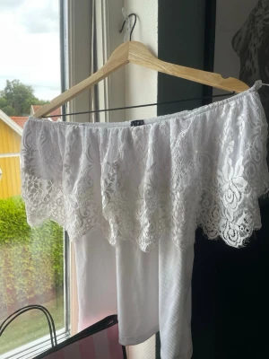 Vit offshoulder topp med spets - Säljer en superfin vit offshoulder topp med bred spetskant och ärmlös design. Toppen är från vero Moda, köpt för dryga en månad sedan utan användning. Toppen säljs ej längre och går inte att hitta i butik. Org pris 499