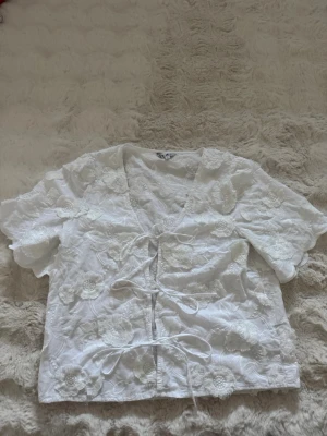 Vit blus med broderade blommor - Söt vit blus från Object med broderade blommor och knytband framtill.