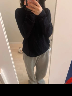 Mysig svart sweatshirt och grå mjukisbyxor - Säljer ett set med en svart sweatshirt och grå mjukisbyxor. Tröjan har rund hals och långa ärmar, byxorna är löst sittande med resår i midjan. Perfekt för chill dagar hemma eller när du vill vara extra bekväm.