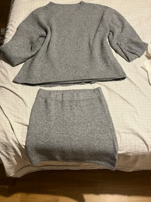 Grått stickat set från SHEIN - Säljer ett mysigt grått stickat set från SHEIN i storlek M. Setet består av en tröja med trekvartsärmar och rund hals samt en matchande kjol med ribbad midja. Perfekt för dig som gillar en enkel och stilren look. Materialet är mjukt och stretchigt. Pris går att diskutera vid snabb affär