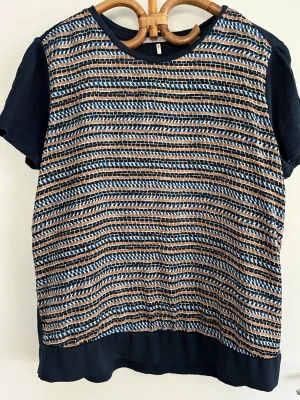 Mönstrad t-shirt från Scotch & Soda - Säljer en snygg t-shirt från Scotch & Soda med korta ärmar. T-shirten har ett unikt randigt mönster i blått, brunt och vitt samt marinblå detaljer vid hals och ärmslut. Baksidan är delvis transparent.  Tillverkad i polyester, perfekt för dig som gillar coola kläder som vågar sticka ut. 