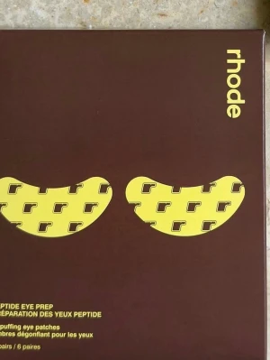 Rhode Peptide Eye Prep ögonmasker - Rhode Peptide Eye Prep är avsvällande ögonmasker i sex par, perfekta för att fräscha upp huden under ögonen. Kommer i bruna förpackningar med gul text och grafisk design. Innehåller peptider som hjälper till att minska svullnad och ge en piggare look.