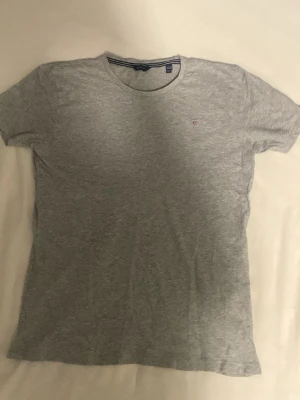Gant t shirt grå - Grå Gant t shirt perfect till jeans. Den har ett litet hål på ryggen men inget man ser så.