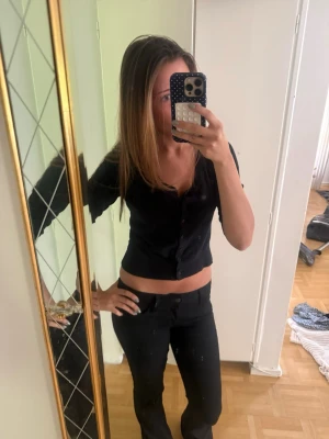 Marinblå croppad topp med knappar - Säljer en marinblå croppad topp med knappar framtill. Toppen har korta ärmar och en figurnära passform som framhäver midjan. Perfekt till jeans eller kjol för en trendig look.