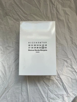 Maison margiela gats  - Maison Martin Margiela parfym i elegant vit förpackning med minimalistisk design och märkets ikoniska numrering på framsidan. Boxen är rektangulär och har en stilren, modern look som passar perfekt för dig som gillar stil. Det enda fel är att boxen har tagit lite stryk. 