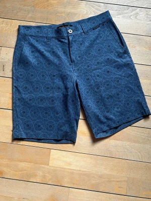 Marinblåa golf shorts - Snygga blå shorts med diskret geometriskt mönster och normal passform. Perfekta för varma dagar och ger en stilren vibe till din outfit. De är helt nya och oanvända!