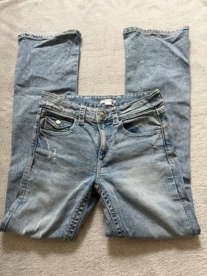 Ljusblå slitna bootcut jeans från Gina Tricot  -  Jag säljer ett par ljusblåa jeans med bootcut och slitningar på både lår och knän. 