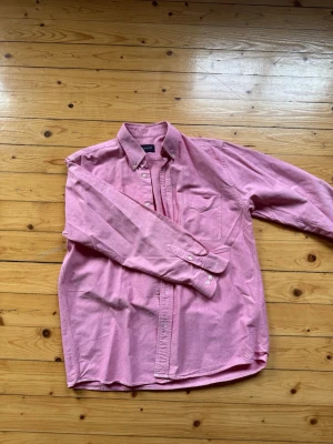 Rosa skjorta från GANT i bomull - Säljer en klassisk rosa skjorta från GANT i mjuk bomull. Skjortan har lång ärm, knappar framtill och button-down krage. Perfekt för en avslappnad men ändå stilren look.