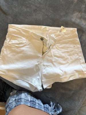 Vita höga shorts med dragkedja - Snygga vita shorts med hög midja och klassisk femficksdesign. De har dragkedja och knapp framtill samt uppvikta benslut för en fräsch look. Pris kan diskuteras 