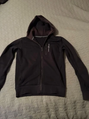 Sail racing zip hoodie - Svart hoodie med hel dragkedja framtill och huva. Modellen har långa ärmar och 1 ficka på bröstet . En liten vit logga finns på bröstet. Perfekt för en avslappnad och stilren look.