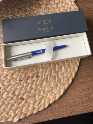 Blå kulspetspenna Parker i presentask - Säljer en blå kulspetspenna från Parker i elegant presentask. Pennan har metalliskt silverfärgat clip och tryckknapp samt blå kropp med tryckt logga. Perfekt som present eller till skrivbordet.
