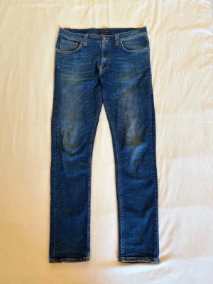 Nudie lean Dean  - Snygga blå slim fit jeans med lätt slitna detaljer och klassisk femficksdesign. Jeansen har en något tvättad look och raka ben. Perfekta för en avslappnad och trendig stil. Materialet är troligtvis bomull med lite stretch för extra komfort. 2% elastan. W32 L32. Pris kan diskuteras vid snabb affär