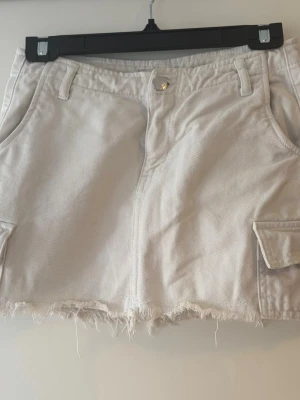 Gina tricot - ljusbeige jeanskjol💕 - Säljer en beige minikjol med jeansliknande tyg som har en fransig, rå kant nertill och fickor både fram och bak. Från Gina tricot i storlek 32. Den har inga defekter, är använd fåtal gånger. Tveka inte att kontakta vid fler frågor💖💖