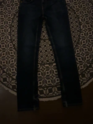 Mörkblå slim fit jeans - Snygga mörkblå slim fit jeans med klassisk femficksdesign och smala ben. Jeansen har en stilren look och passar perfekt till en avslappnad streetstyle. Tillverkade i denim med lätt stretch för extra komfort.