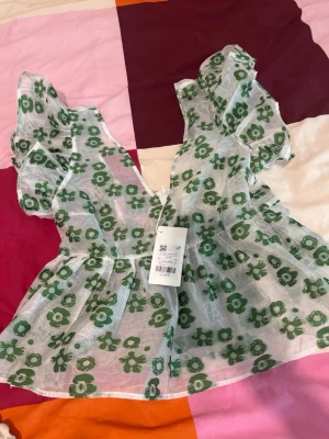 Blommig blus med volangärmar - Söt blus i transparent vitt tyg med grönt blommönster. Helt nytt med prislapp, nytt pris 600 och mitt pris 260