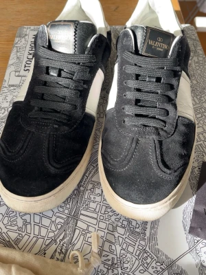 Valentino svartvita sneakers - Snygga sneakers från Valentino i svart mocka med vita detaljer och vit sula. nån spik av kom me mer frågor