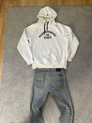 Åre peak performance hoodie  - Snygg vit hoodie från Peak Performance med svart text och snören. Klassisk känguruficka framtill och huva med dragsko. Perfekt för en laidback stil. Riktigt snygg! Storlek = XL 