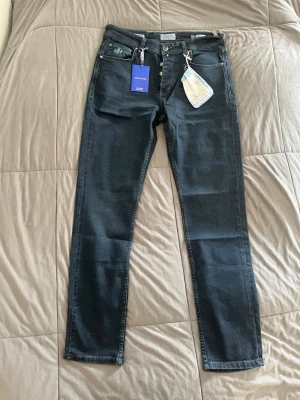 Jacob cohen jeans  - Snygga mörkblå jeans med rak passform och klassisk femficksdesign. Jeansen har silverfärgade knappar och detaljer samt etiketter kvar. Perfekta för dig som gillar en stilren look och vill ha ett par jeans som funkar till det mesta.