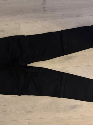 Svarta chinos med smal passform - Snygga svarta chinos med smal passform och klassisk design. Byxorna har raka ben och två bakfickor med knapp. Perfekta för dig som vill ha en clean och stilren look.