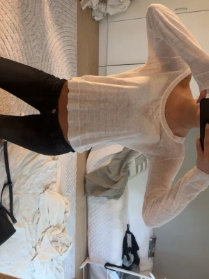 Vit croppad långärmad topp - Säljer en tunn, vit croppad topp med lång ärm och bred urringning som kan bäras offshoulder. Toppen har en lätt transparent look och är perfekt för lager på lager. Passar dig som gillar en enkel men trendig stil.