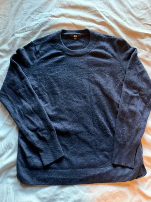Mörkblå cashmere tröja från Uniqlo - Mysig mörkblå stickad tröja från Uniqlo i storlek XL, passar även L. Tröjan har rund halsringning, långa ärmar och ribbade muddar vid ärmslut och nederkant. Perfekt för lager på lager under kyliga dagar. Pris kan diskuteras 