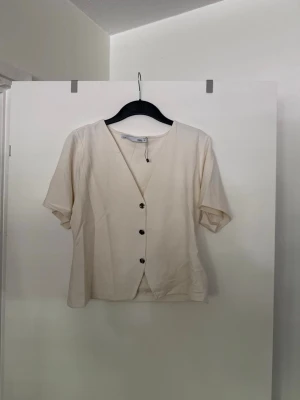 Vit t-shirt med knappar  - Storlek XL. Liten i storlek. Aldrig använd. 