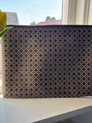Malene Birger datorfodral  - Snygg kuvertväska med rutigt mönster i brunt, beige och svart. Lite skav i nedre hörnen och om man vill kunna stänga måste man fixa dragkedjan. 