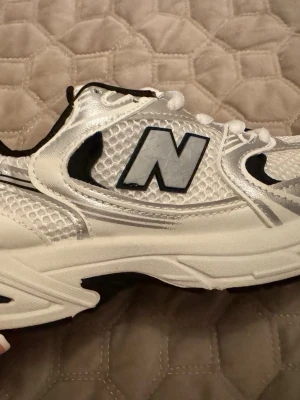 New Balance 530  - 🤍 New Balance 530 – Vit/Silver 🤍  ✅ Klassisk New Balance-design 👟 ✅ Stilren kombination av vitt, silver och svarta detaljer ✨ ✅ Lätt och bekväm passform för hela dagen ☁️ ✅ Ventilerande ovandel i mesh för extra komfort 🌬️ ✅ Perfekta till både vardag, promenader och träning 🏃‍♂️ ✅ Trendig modell som passar alla outfits 🔥  ✨ New Balance 530 är en av de mest populära sneakersmodellerna tack vare sin snygga retrodesign och höga komfort. Ett perfekt val för dig som vill kombinera stil och bekvämlighet i e