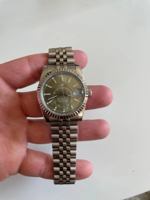 Seiko silverfärgad klocka i metall - Stilren Seiko klocka i silverfärgad metall med klassisk länkarmband och räfflad bezel. Urtavlan har tydliga markeringar och datumvisning. Lysande index för enkel avläsning i mörker..