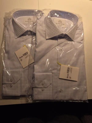 Blårutig skjorta från The Shirt Factory - Säljer en klassisk blårutig skjorta från The Shirt Factory i slim fit. Skjortan är vit med tunna blå rutor, har långa ärmar och knappar framtill. Perfekt för dig som gillar stilrena och tidlösa plagg. 250kr st. 