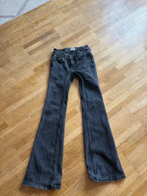 Svarta bootcut jeans från 197 - Snygga svarta bootcut jeans från 197 med klassisk femficksmodell och låg midja. Jeansen har vida ben och är tillverkade i mjuk denim som ger en skön passform. Perfekta för dig som gillar retrovibbar och vill ha ett par jeans som sticker ut.