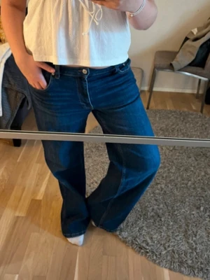 Mörkblå  jeans - Säljer ett par mörkblå bootcut jeans med medel midja och klassisk femficksmodell. Jeansen har raka, vida ben och är tillverkade i ett mjukt denimtyg som ger en avslappnad men snygg look. Perfekta till en enkel topp eller hoodie.