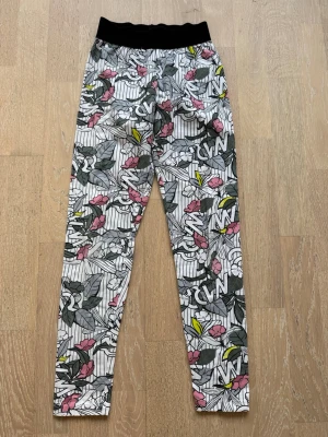 Mönstrade leggings med blommor - Snygga leggings med svart resår i midjan och ett färgglatt blommönster i rosa, grått, vitt och gult. Tryckt text och grafiska detaljer. 