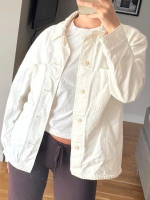 Vit overshirt med fickor - Stilren vit overshirt i bomull med knäppning framtill och två stora bröstfickor. Rak passform och klassisk krage ger en clean look. Perfekt att slänga över en t-shirt för en avslappnad vibe.